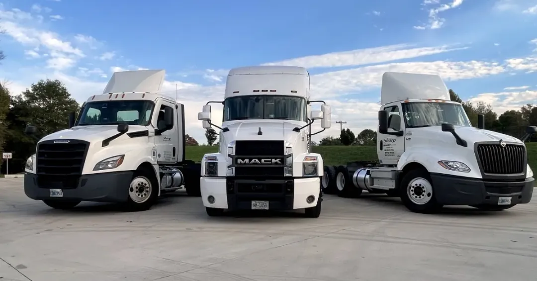 Three Company Driver trucks at Sharp Transit are Mack, International, and Freightliner daycabs